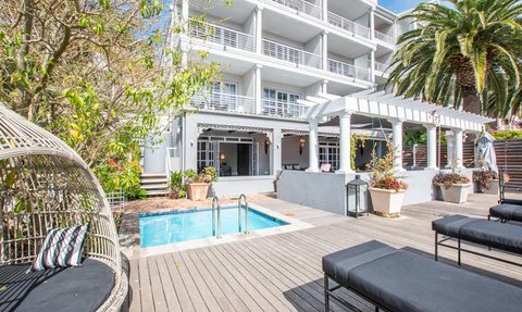 Ein eleganter Außenbereich mit einem kleinen Pool, umgeben von modernen Liegen und üppigem Grün.