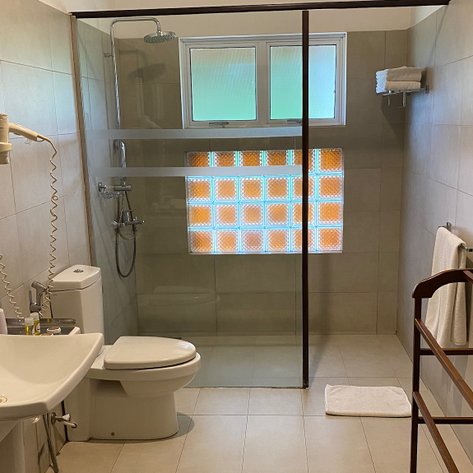 Ein modernes Badezimmer mit einer gläsernen Duschkabine und einem großen Fenster, das natürliches Licht hereinlässt.