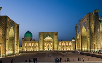 Die beeindruckende Architektur der Registan in Samarkand erstrahlt in warmem Licht, während Menschen die Szenerie genießen.