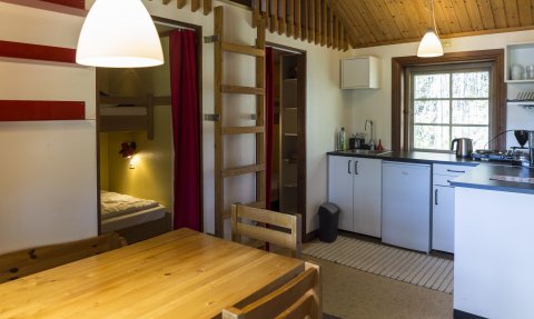 Die Innenansicht einer gemütlichen Ferienhütte mit Holzdekor, einer Küche und einem Esstisch aus Holz.