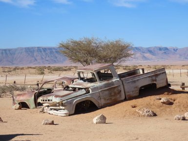 Ein rostiges Auto steht verlassen in der Wüste - Namibia mit Kindern