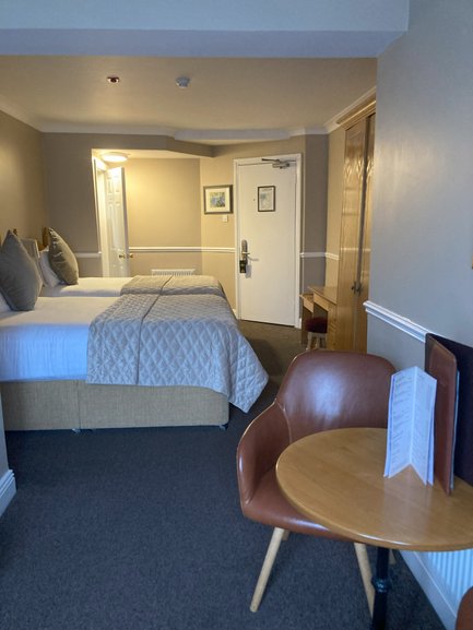 Ein gemütliches Hotelzimmer mit zwei Betten, einem kleinen Tisch und einem Stuhl, ideal für Entspannung und Erholung.