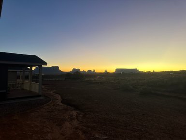 Die Silhouette der Monument Valley Felsen hebt sich gegen den farbenfrohen Sonnenuntergang ab, während ein ruhiger Abend naht.
