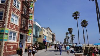Die belebte Santa Monica Promenade zeigt Spaziergänger, Palmen und bunte Geschäfte unter strahlend blauem Himmel.