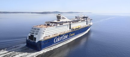 Ein großes Kreuzfahrtschiff mit der Aufschrift 'Color Line' fährt ruhig über das glitzernde Wasser unter einem klaren Himmel.