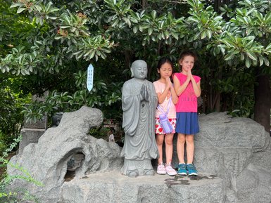Kinder posieren neben traditionellen Statuen vor der Großen Wildganspagode in Xi’an – China Reise mit Kindern