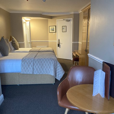 Ein gemütliches Hotelzimmer mit zwei Betten, einem kleinen Tisch und einem Stuhl, ideal für Entspannung und Erholung.