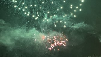 Ein beeindruckendes Feuerwerk erhellt den Nachthimmel über einer verschneiten Landschaft, während Menschen gebannt zuschauen.