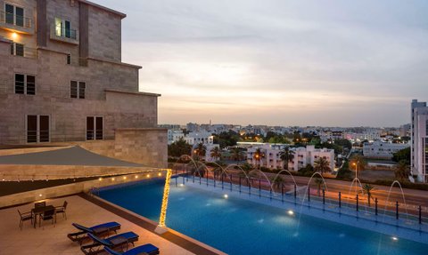 Außenpool mit Ausblick auf Muscat im Radisson Hotel Muscat Panorama bei Sonnenuntergang - Oman Familienreise