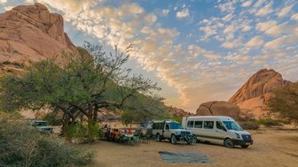 Eine Reisegruppe sitzt an einem Campingtische - Namibia mit Jugendlichen