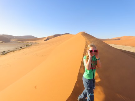Ein Kind läuft eine Düne hinauf - Namibia Urlaub mit Kindern