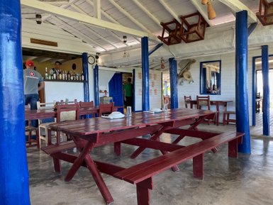 Ein rustikales Restaurant mit roten Holztischen und blauen Säulen, das eine einladende Atmosphäre ausstrahlt.