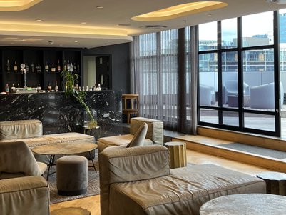 Ein eleganter Lobbybereich mit bequemen, hellen Sofas und einem stilvollen Tisch, umgeben von großen Fenstern.