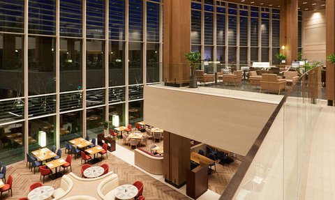 Ein eleganter Lobbybereich mit großen Fenstern, die den Blick auf die Stadt bei Nacht freigeben, und stilvollen Sitzgelegenheiten.