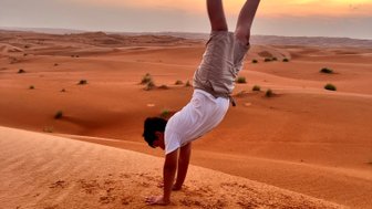 Junge macht Handstand in der Wahiba-Wüste beim Sonnenuntergang – Oman Reise mit Kindern