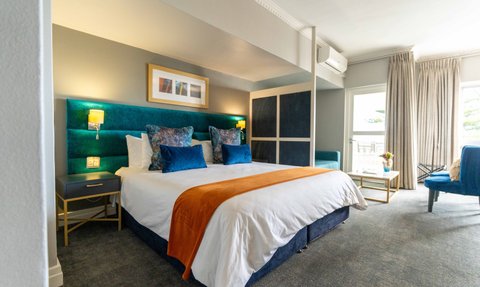 Ein stilvolles Hotelzimmer mit einem großen Bett, das mit blauen Kissen und einer orangefarbenen Decke dekoriert ist.