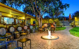 Zwei Musiker spielen Gitarre am Lagerfeuer, umgeben von gemütlichen Sitzgelegenheiten und einer einladenden Atmosphäre.