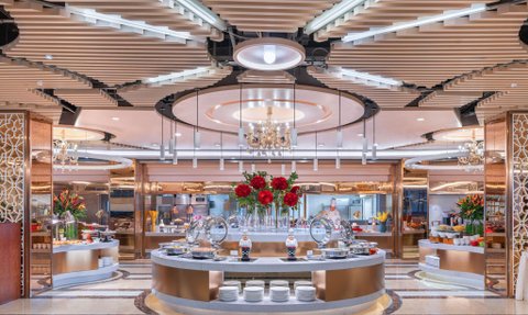 Ein eleganter Buffetbereich mit stilvollen Möbeln, üppigen Blumenarrangements und einem offenen Küchenbereich im Hintergrund.