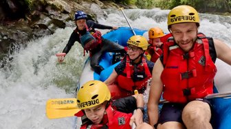 Familie im Schlauchboot während sie den Fluss hinunterfährt – Malaysia & Borneo Familienreise