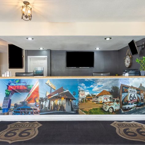 Die Rezeption eines Motels mit einem bunten Wandbild, das historische Autos und Route 66 zeigt, strahlt nostalgischen Charme aus.