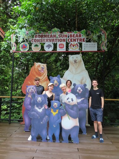 Familie posiert mit lebensgroßen Nachbildungen von Sonnenbären im Sun Bear Sanctuary – Malaysia & Borneo Familienreise