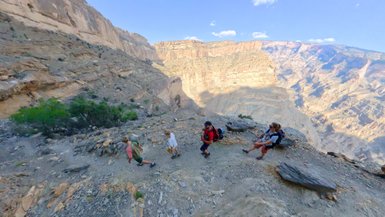 Familie erkundet zu Fuß die beeindruckende Berglandschaft und Felsformationen des Jebel Shams – Oman Familienreise