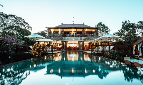 Ein luxuriöses Resort in Bali mit einem glitzernden Pool und einer eleganten Terrasse, umgeben von üppiger Vegetation.