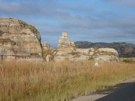 Im Isalo-Nationalpark erheben sich beeindruckende Felsformationen über hohes, goldenes Gras unter einem bewölkten Himmel.