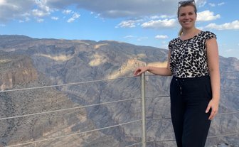 Frau steht vor der Felslandschaft des Jebel Shams und lässt sich fotografieren – Oman Familienreise