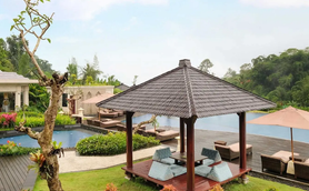 Ein stilvoller Pavillon mit bequemen Sitzgelegenheiten steht in einem üppigen Garten neben einem glitzernden Pool.