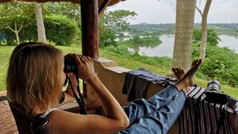 Eine Person sitzt entspannt auf einer Veranda und fotografiert mit einer Kamera die malerische Landschaft im Hintergrund.