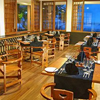 Ein elegantes Restaurant mit Holzmöbeln und Tischen, die für Gäste gedeckt sind, bietet eine einladende Atmosphäre.