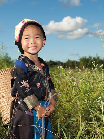 Einheimisches Kind zwischen grünen Teesträuchern in einer Teeplantage – China mit Kindern