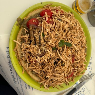 Ein Teller mit einer üppigen Portion italienischer Spezialität, garniert mit frischen Tomaten und knusprigen Streifen.