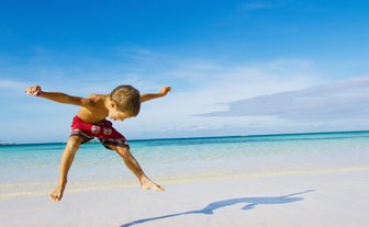 Junge springt am Sandstrand von Mexiko – Mexiko Familienreise