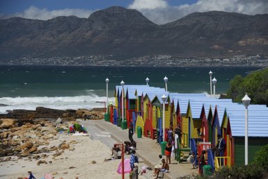 Farbenfrohe Strandhäuschen und badende Familien am St James Beach bei Kapstadt – Garden Route mit Kindern