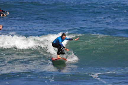 Eine Surferin in einem blauen Neoprenanzug reitet auf einer Welle und zeigt Geschicklichkeit und Balance.