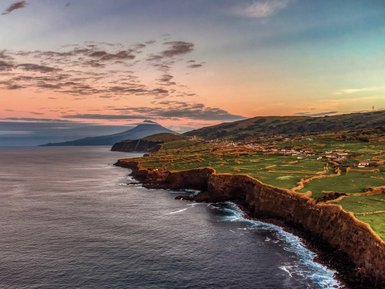 Eine atemberaubende Küstenlandschaft mit sanften Hügeln und einem ruhigen Ozean, beleuchtet von einem sanften Sonnenuntergang.