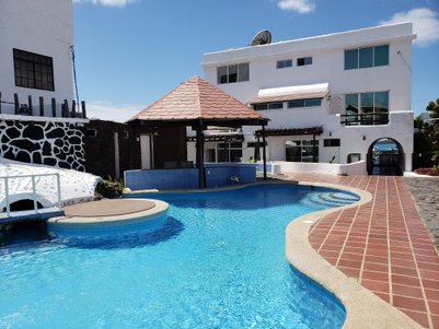 Ein einladender Pool mit klarem Wasser, umgeben von einer modernen weißen Villa und einem schattigen Pavillon.