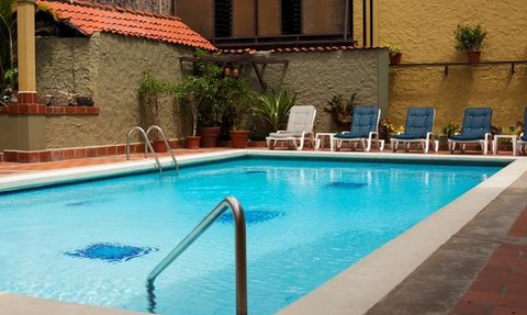 Ein einladender Pool mit klarem Wasser, umgeben von Liegen und üppigen Pflanzen in einem ruhigen Hotelgarten.