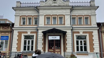 Eine historische Bahnhofsgebäude mit einem großen Uhr und einem eleganten Dach, umgeben von grauem Himmel.
