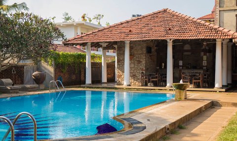 Ein einladender Poolbereich mit klarem Wasser, umgeben von tropischen Pflanzen und einem schattigen Pavillon.