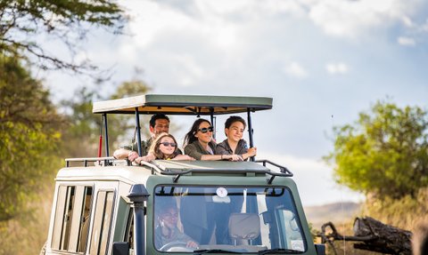 Familiengruppe mit Guide auf Safari im offenen Jeep – Tansania Familienreise
