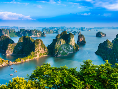Eine atemberaubende Aussicht auf die Kalksteininseln von Ha Long Bay, umgeben von klarem, blauem Wasser und grünem Laub.