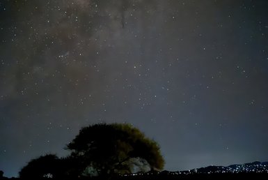Ein klarer Nachthimmel voller funkelnder Sterne, mit der Milchstraße, die sich majestätisch über die Szene erstreckt.