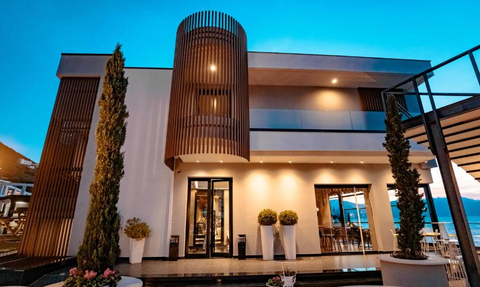 Das moderne Hotelgebäude mit Holzverkleidung und großen Fenstern strahlt Eleganz und Stil aus, umgeben von grünen Pflanzen.