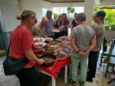 Eine Gruppe von Menschen steht an einem Tisch mit verschiedenen Gerichten, während sie sich zum Essen bereit machen.