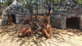 Ein Mann versucht mit einem Holzstab ein Feuer zu entzünden - Namibia Urlaub mit Kindern