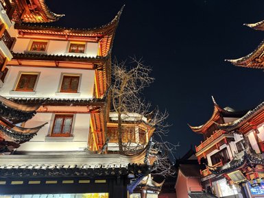 Die beeindruckende Architektur traditioneller Gebäude mit geschwungenen Dächern erstrahlt in der nächtlichen Beleuchtung.