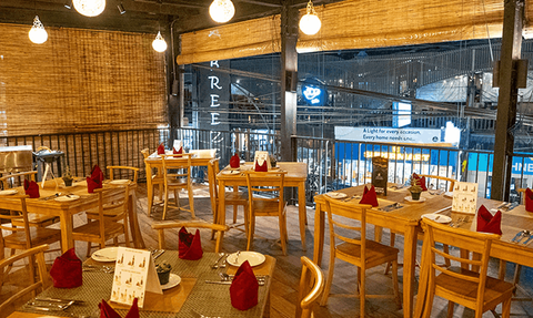 Ein stilvolles Restaurant mit Holztischen, eleganten roten Servietten und warmem Licht schafft eine einladende Atmosphäre.